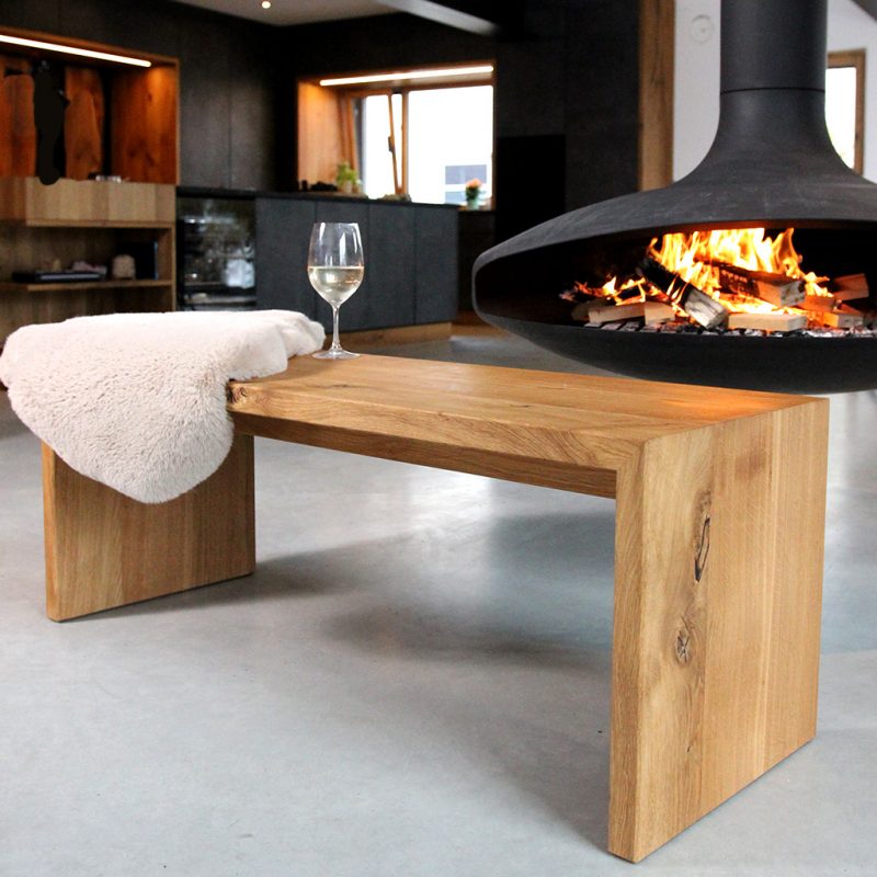 Solid wood bench made of wild oak in a modern living room and fireplace, cozy with wine