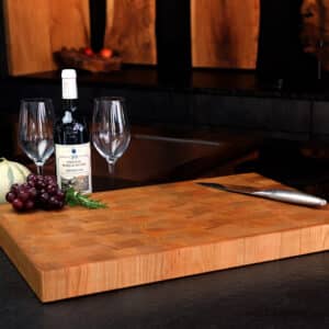 Stirnholz Schneidebrett Aus Kirsche In Moderner Küche, Hochwertige Messer Und Weintrauben, Und Weindekoration Im Hintergrund